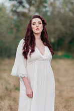 Beautiful, full figured woman in light and airy white nightgown. The gown has three-quarter sleeves with a white embroidered trim, a pretty v-neckline trimmed with white embroidery and an empire waist with embroidered trim.