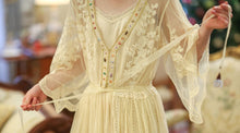 This is a close up image of top and waist of this beautiful set. This elegant nightgown is a two-piece set with a lovely silky satin chemise that's worn under a soft, stretchy textured layer of pure golden glamour.  The champagne-colored chemise has adjustable spaghetti straps and falls above the knee. The soft, stretchy over layer falls low to mid-calf. It's graceful and flowing with three-quarter bell sleeves and waist tie. It's gorgeous ya'll.!