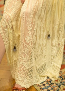 This is a close up view of the skirt on this elegant nightgown. This elegant nightgown is a two-piece set with a lovely silky satin chemise that's worn under a soft, stretchy textured layer of pure golden glamour.  The champagne-colored chemise has adjustable spaghetti straps and falls above the knee. The soft, stretchy overlayer falls low to mid-calf. It's graceful and flowing with three-quarter bell sleeves and waist tie. It's gorgeous ya'll