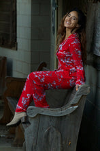 Beautiful woman wearing richly colored red pajamas with white floral design. These pajamas are made from hand-pulled Peruvian Pima cotton, known for its silky luster and soft hand, combined with modal give the perfect drape, stretch and recovery to these traditional style pajamas by Cat's Pajamas from Margaret Lawton. XS to 2XL