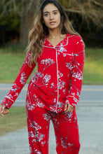 Close up of beautiful woman wearing richly colored red pajamas with white floral design. These pajamas are made from hand-pulled Peruvian Pima cotton, known for its silky luster and soft hand, combined with modal give the perfect drape, stretch and recovery to these traditional style pajamas by Cat's Pajamas from Margaret Lawton. XS to 2XL