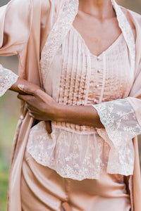 Close up view of silky-smooth lace trimmed pajama top with elegant flat felled seams and pearl buttonsand robe collar and cuffs. Silky smooth satin with soft lace.