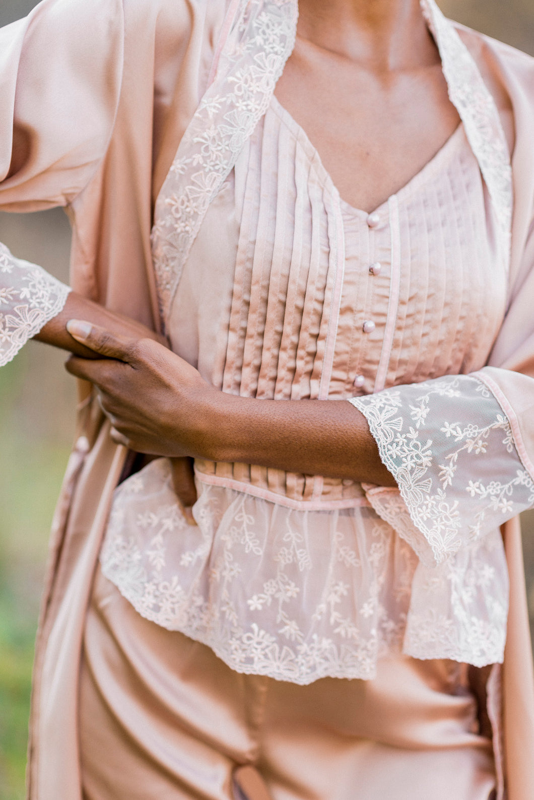 Close up view of silky-smooth lace trimmed pajama top with elegant flat felled seams and pearl buttonsand robe collar and cuffs. Silky smooth satin with soft lace.