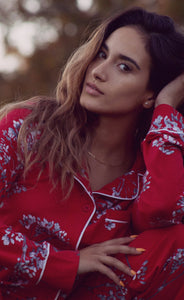 Close up of beautiful woman wearing richly colored red pajamas with white floral design. These pajamas are made from hand-pulled Peruvian Pima cotton, known for its silky luster and soft hand, combined with modal give the perfect drape, stretch and recovery to these traditional style pajamas by Cat's Pajamas from Margaret Lawton. XS to 2XL