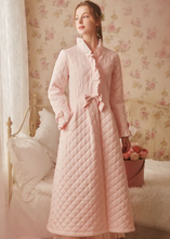 Pretty pink quilted robe. Warm and soft, it feels like a snuggly warm blanket for cold nights and mornings.  Made with soft 100% cotton and lovely features for comfort and elegance in beautiful powder pink.  A full snap front allows you to wrap and unwrap with ease, and a pleated back gives you room just where you need it. Ruffled cuffs and collar add a feminine touch, and satin bows at the waist and sleeves transform this winter robe into something quite fancy. 