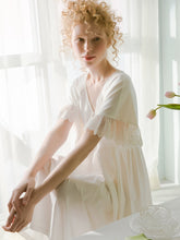 Side image of a woman sitting in a chair wearing a Sweet Autumn Vintage Nightgown from Margaret Lawton Nightgowns. Loose fit, small cloth covered buttons and graceful lace short butterfly sleeves. Falls at the knee.