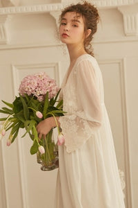 This elegant peignoir is the ultimate in feminine grace. The transparent robe features a gorgeous, embroidered bodice punctuated by three pearl buttons and a beautiful ruffle. The robe is a simple design of soft material, with spaghetti straps and deep v-neck trimmed with soft scalloped lace. 