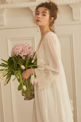 This elegant peignoir is the ultimate in feminine grace. The transparent robe features a gorgeous, embroidered bodice punctuated by three pearl buttons and a beautiful ruffle. The robe is a simple design of soft material, with spaghetti straps and deep v-neck trimmed with soft scalloped lace. 