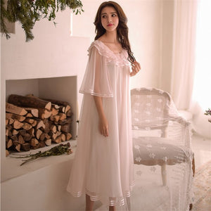 Image of a woman standing wearing a Dreamy Margaret Lawton Nightgown.  Transparent chiffon trimmed with satin ribbon overlays cotton underlayer.